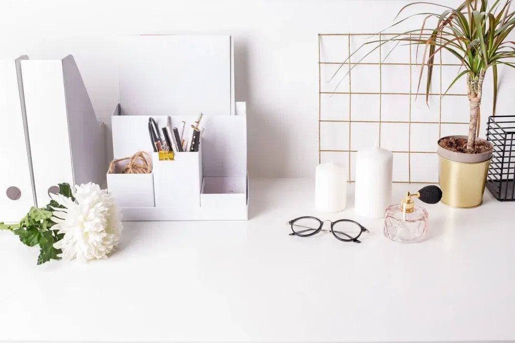 Bright, minimalist white desk with a tidy organizer, glasses, and a single white flower — visual metaphor for a clean, single-source-of-truth tech stack