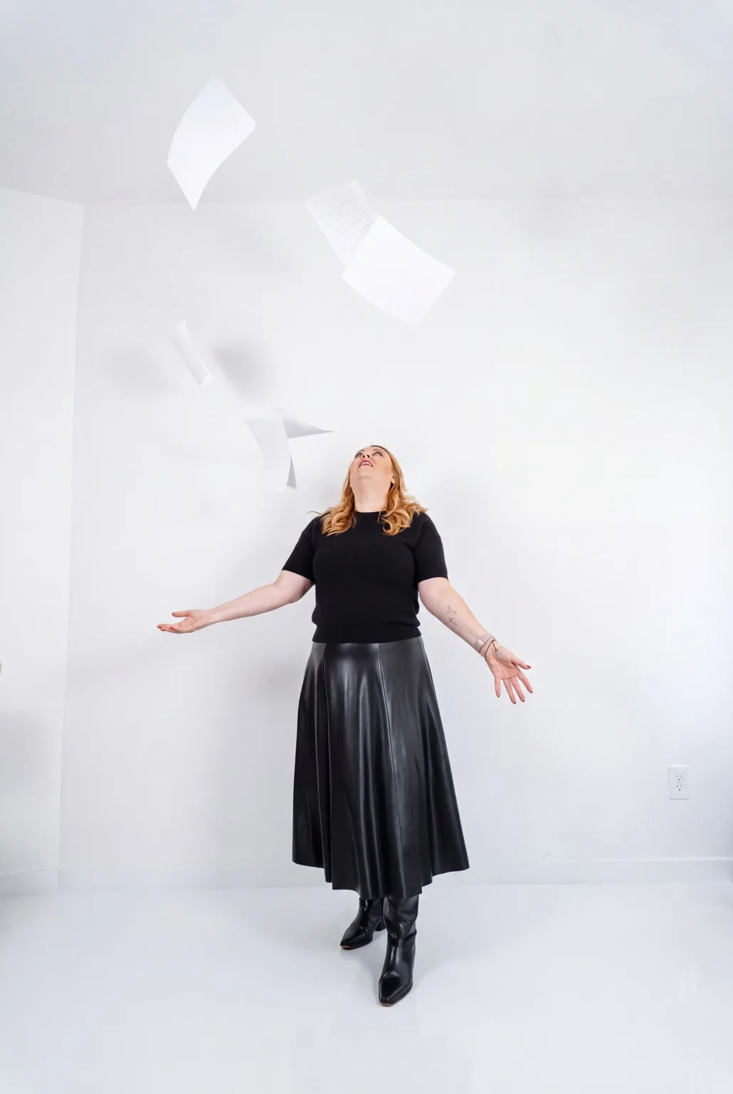Andrea tossing papers into the air during a creative photoshoot