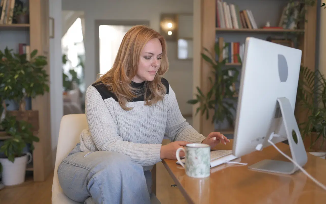 Professional woman working at desktop computer in home office while managing remote work and career tasks